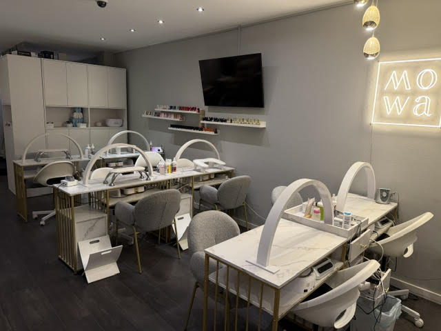 Großer Maniküre-Bereich mit Neon-Logo und Nagellack-Regalen bei MOWA